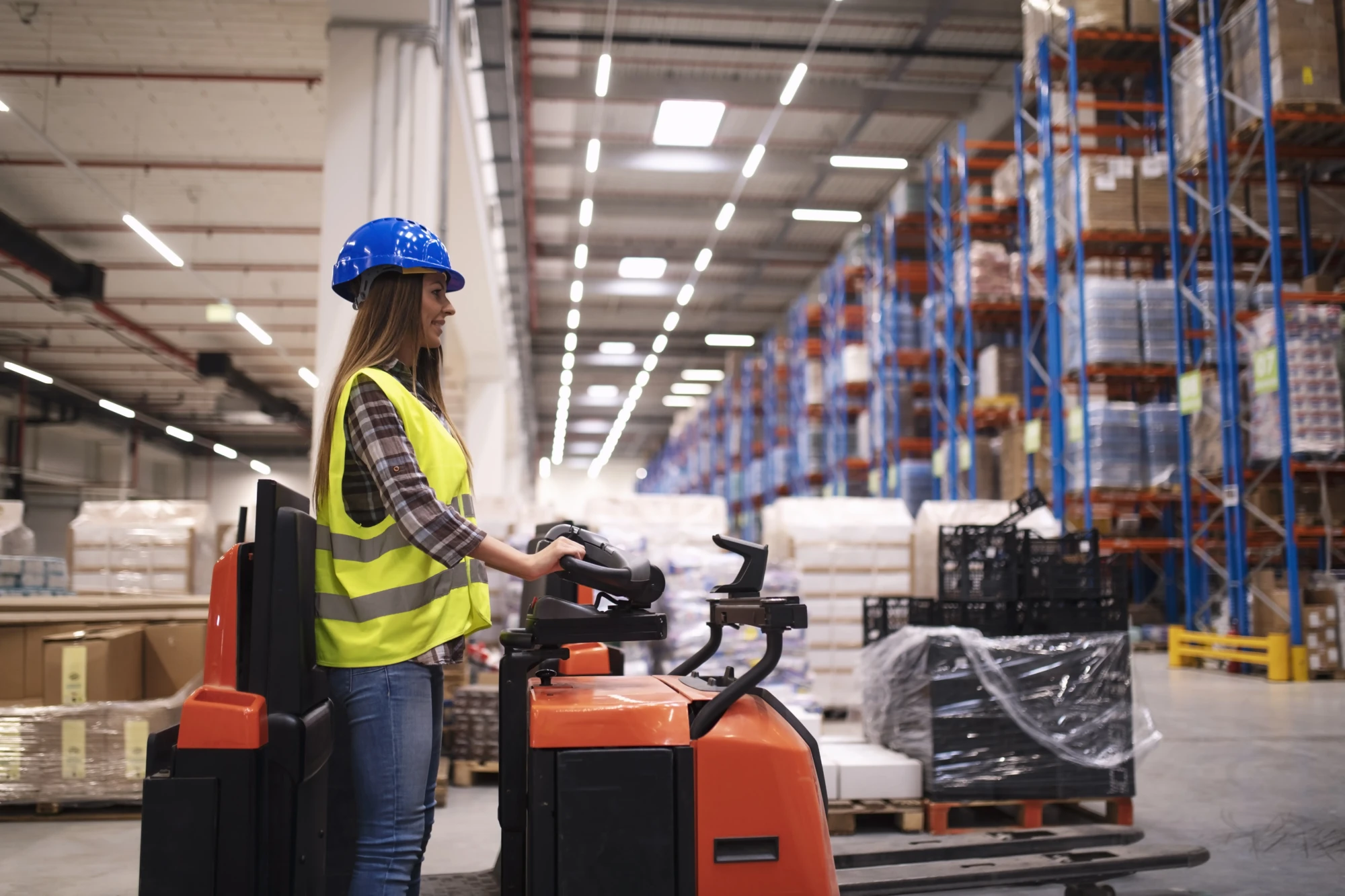 femme-ouvrier-d-entrepot-d-exploitation-de-la-machine-de-chariot-elevateur-dans-un-grand-centre-d-entrepot-de-distribution